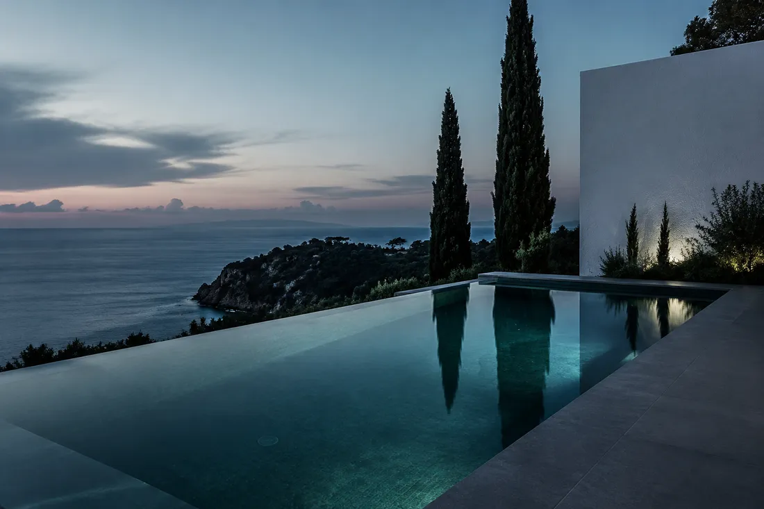 Piscina desbordante de tonos grafito sobre la costa mediterránea al atardecer